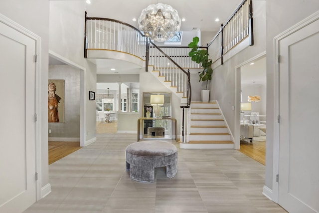 tiled foyer featuring a high ceiling, plenty of natural light, baseboards, and stairs