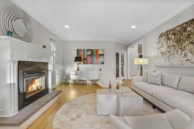 living room featuring recessed lighting, wood finished floors, baseboards, ornamental molding, and a glass covered fireplace