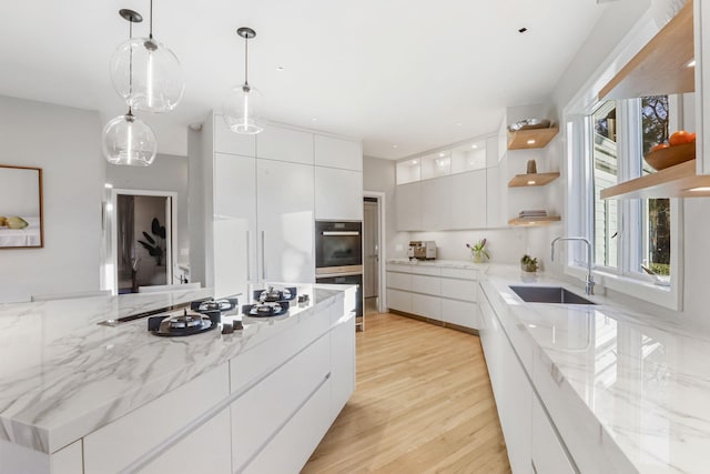 kitchen with white cabinets, modern cabinets, double oven, open shelves, and a sink