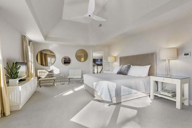 bedroom featuring a tray ceiling, light colored carpet, visible vents, a ceiling fan, and vaulted ceiling