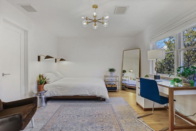 bedroom with light wood finished floors, visible vents, and a notable chandelier