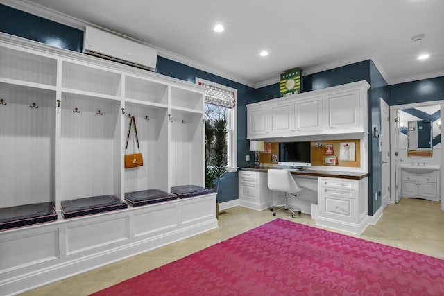 mudroom featuring an AC wall unit, crown molding, built in desk, and a sink