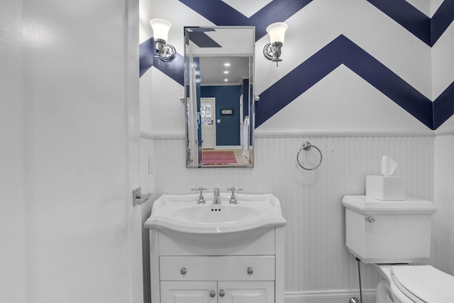 bathroom featuring toilet, a wainscoted wall, and vanity