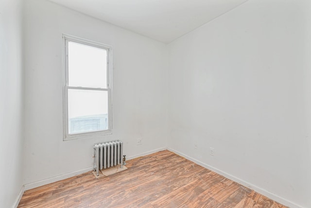 empty room with hardwood / wood-style floors and radiator heating unit