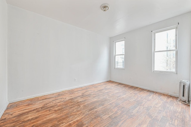 unfurnished room with hardwood / wood-style flooring and radiator heating unit