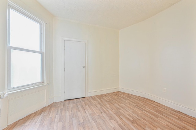 unfurnished room with a textured ceiling and light wood-type flooring