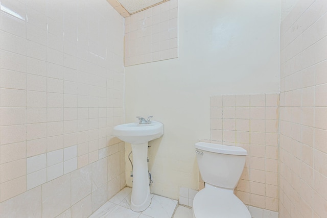 bathroom featuring tile walls and toilet