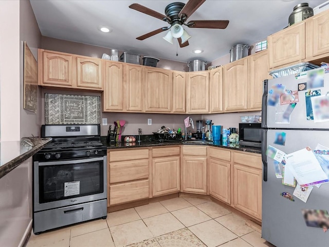 kitchen featuring light tile patterned floors, stainless steel appliances, dark stone counters, and light brown cabinets