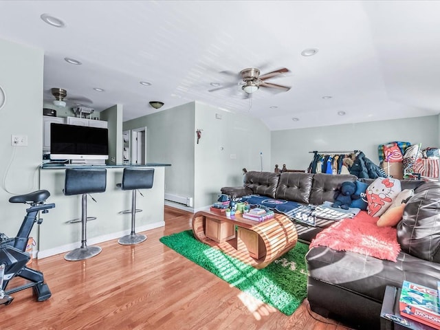 living room featuring ceiling fan, wood-type flooring, and a baseboard heating unit