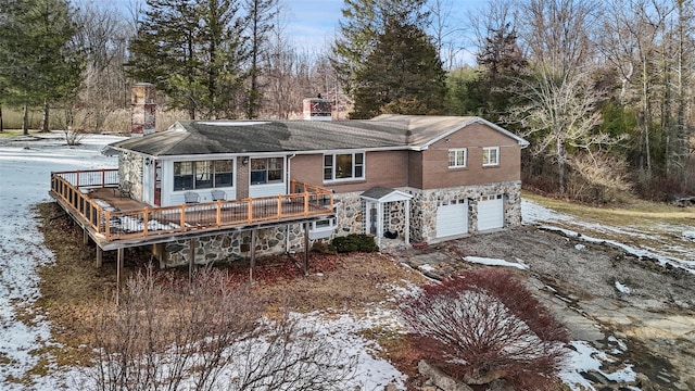 snow covered property featuring a wooden deck and a garage