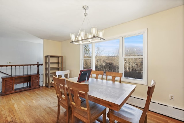 dining area with a baseboard heating unit, an inviting chandelier, and light hardwood / wood-style flooring