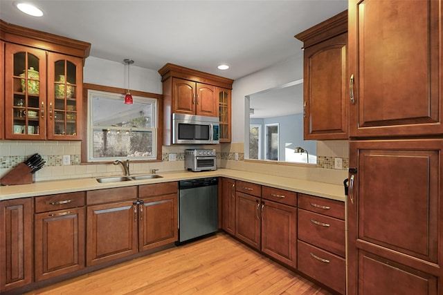 kitchen featuring sink, tasteful backsplash, decorative light fixtures, light hardwood / wood-style flooring, and appliances with stainless steel finishes