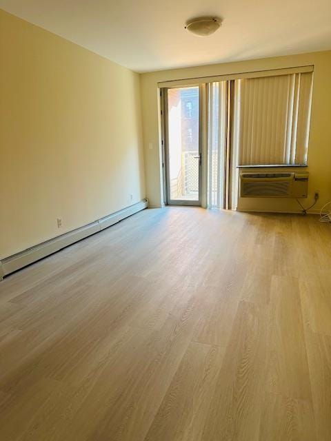 empty room with a wall mounted AC, baseboard heating, and light hardwood / wood-style floors