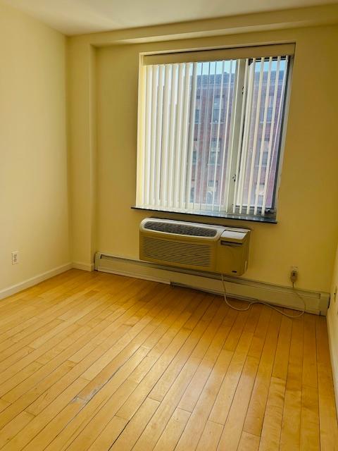 spare room with a wall mounted AC and light hardwood / wood-style flooring