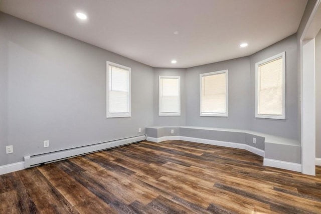 unfurnished room featuring a baseboard radiator and dark hardwood / wood-style flooring