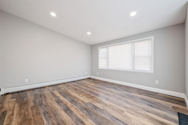 empty room featuring hardwood / wood-style flooring and baseboard heating