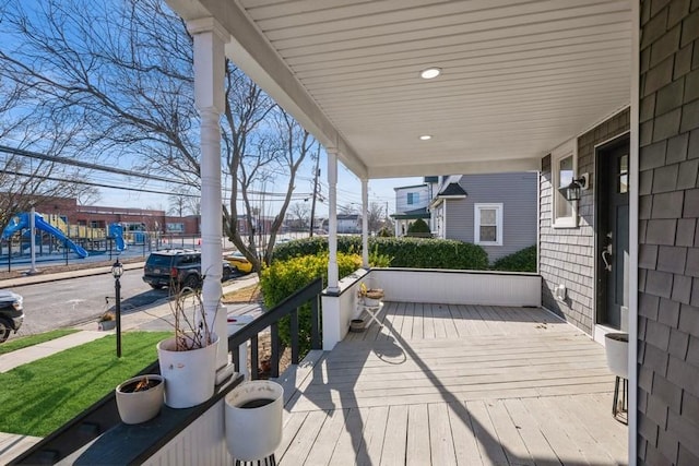 wooden terrace featuring a playground and a porch