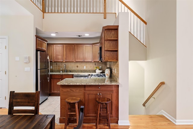 kitchen featuring appliances with stainless steel finishes, sink, a breakfast bar area, light stone counters, and kitchen peninsula