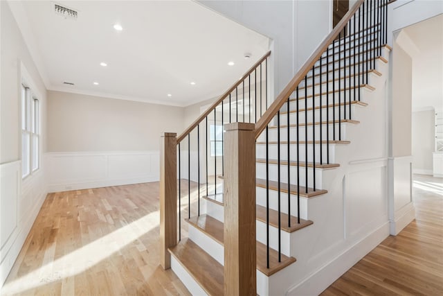 stairs with hardwood / wood-style flooring and crown molding