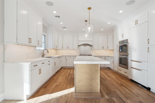 kitchen with white cabinetry, sink, decorative backsplash, and a kitchen island