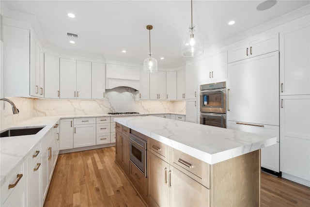 kitchen with a kitchen island, white cabinetry, sink, light stone counters, and stainless steel appliances