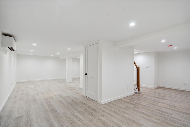 basement with a wall mounted air conditioner and light hardwood / wood-style floors