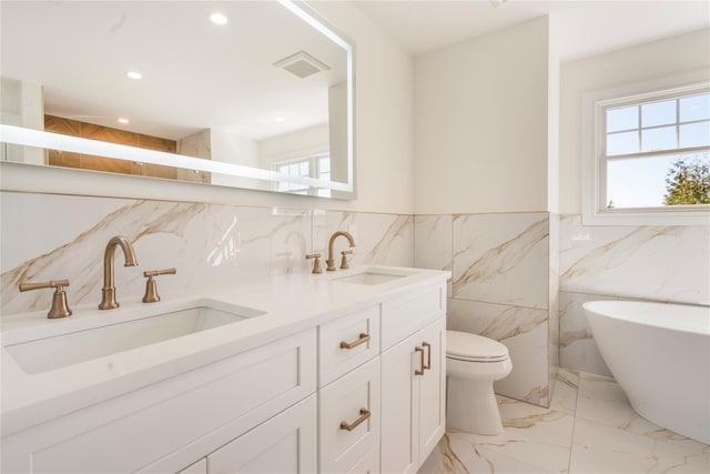 bathroom featuring vanity, a washtub, tile walls, and toilet