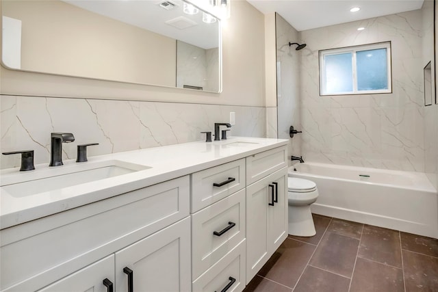 full bathroom with tiled shower / bath, tile walls, vanity, and toilet