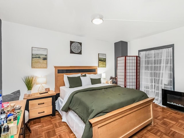 bedroom with a fireplace and dark parquet floors