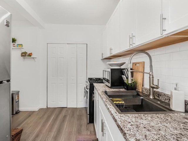 kitchen with white cabinetry, appliances with stainless steel finishes, sink, and light hardwood / wood-style floors