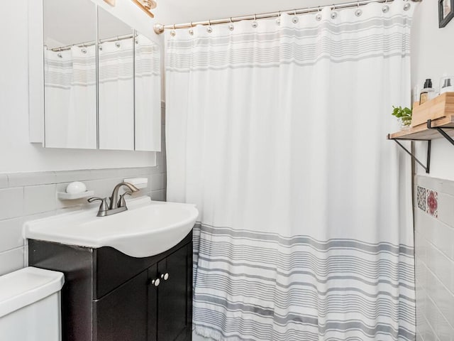 bathroom with tile walls, vanity, and toilet