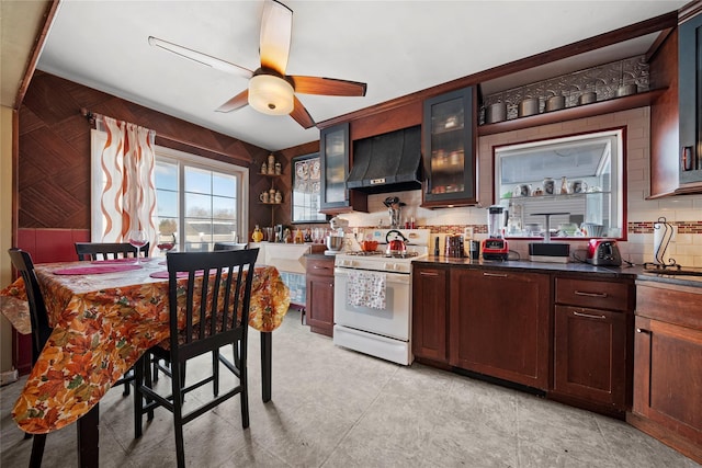 kitchen featuring white gas range, sink, backsplash, ceiling fan, and wall chimney exhaust hood