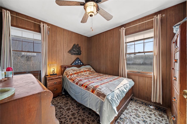 bedroom with ceiling fan and wood walls