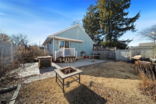 back of property featuring a yard, a patio area, and a fire pit