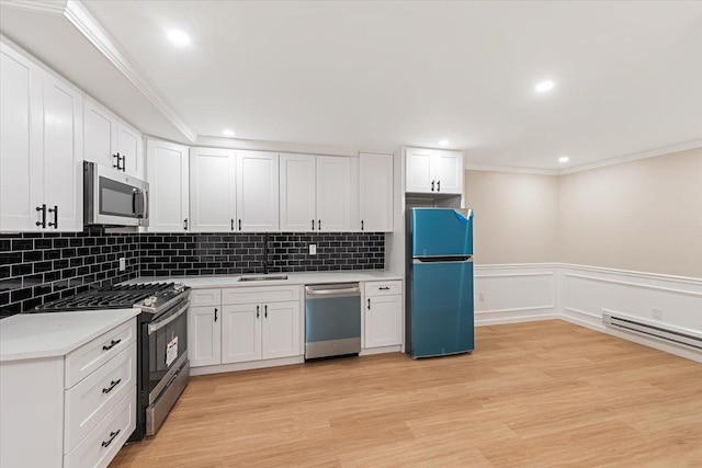 kitchen featuring sink, stainless steel appliances, ornamental molding, white cabinets, and light wood-type flooring