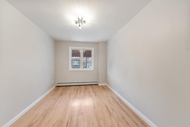 unfurnished room featuring light wood-type flooring and a baseboard heating unit