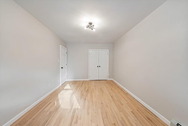 empty room featuring a baseboard heating unit and light hardwood / wood-style floors