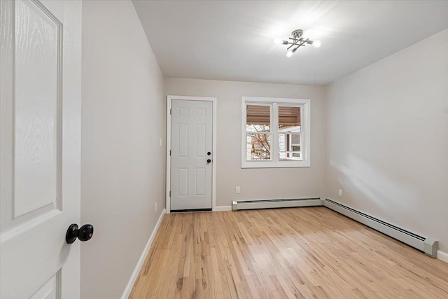 spare room with baseboard heating and light hardwood / wood-style flooring