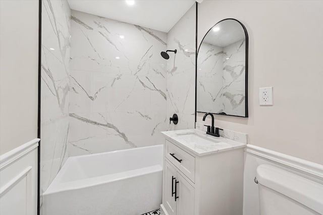 full bathroom featuring vanity, tiled shower / bath combo, and toilet