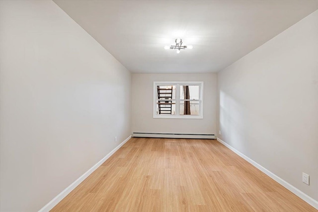 empty room featuring light wood-type flooring and baseboard heating