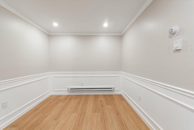 empty room with ornamental molding, a baseboard heating unit, and light wood-type flooring