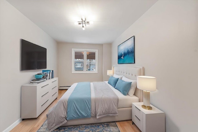 bedroom with a baseboard radiator and light hardwood / wood-style floors