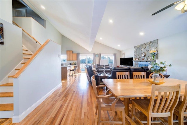 dining area with high vaulted ceiling, ceiling fan, and light hardwood / wood-style flooring