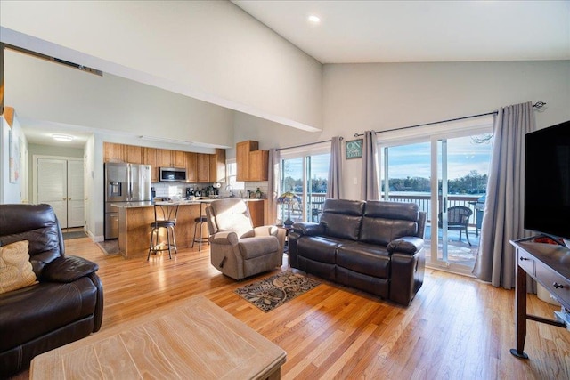 living room featuring high vaulted ceiling and light wood-type flooring