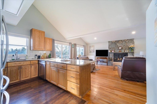 kitchen with appliances with stainless steel finishes, kitchen peninsula, sink, and hardwood / wood-style floors