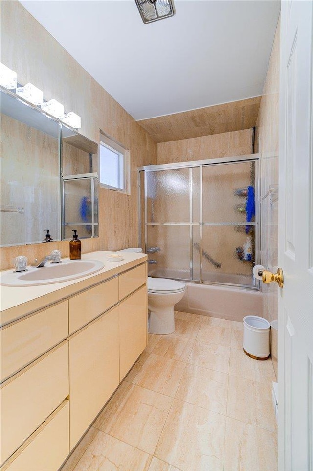 full bathroom featuring vanity, tile patterned floors, shower / bath combination with glass door, and toilet