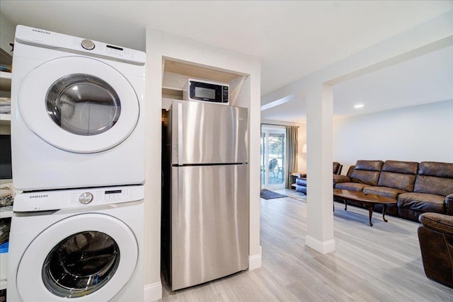 laundry area featuring stacked washer and dryer and light hardwood / wood-style floors