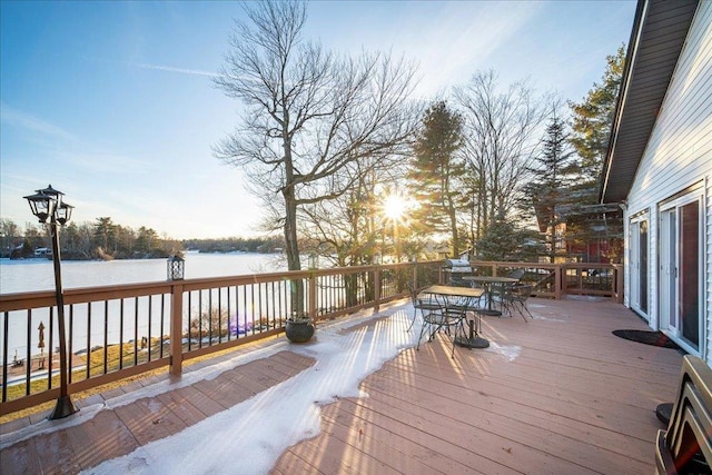 deck at dusk featuring a water view