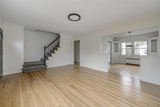 unfurnished living room featuring radiator heating unit and light hardwood / wood-style flooring