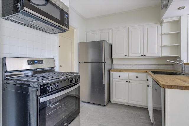 kitchen featuring sink, appliances with stainless steel finishes, butcher block counters, white cabinetry, and backsplash